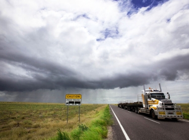 outback road in western queensland with looming storm in the wet season. weather storm sign road transport