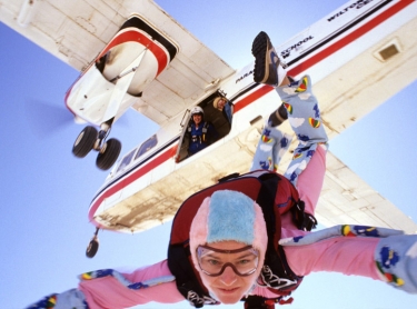 Skydiver Ginette Kenney leaps from an aircraft near Sydney, in Australia, while two other parachutists look out the door.
